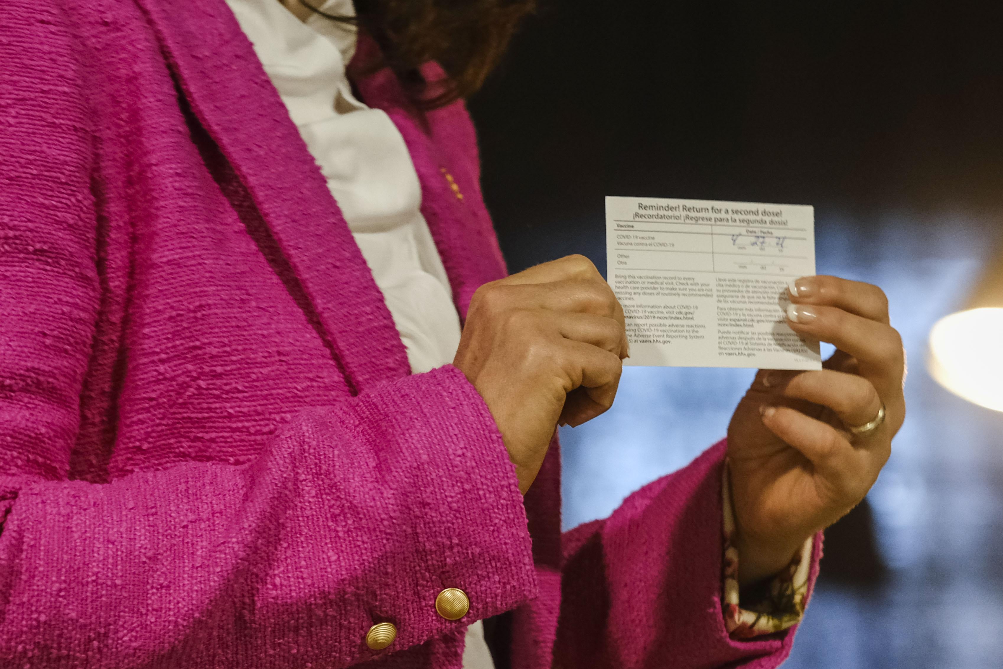 A woman shows holds her vaccine card in her hands.