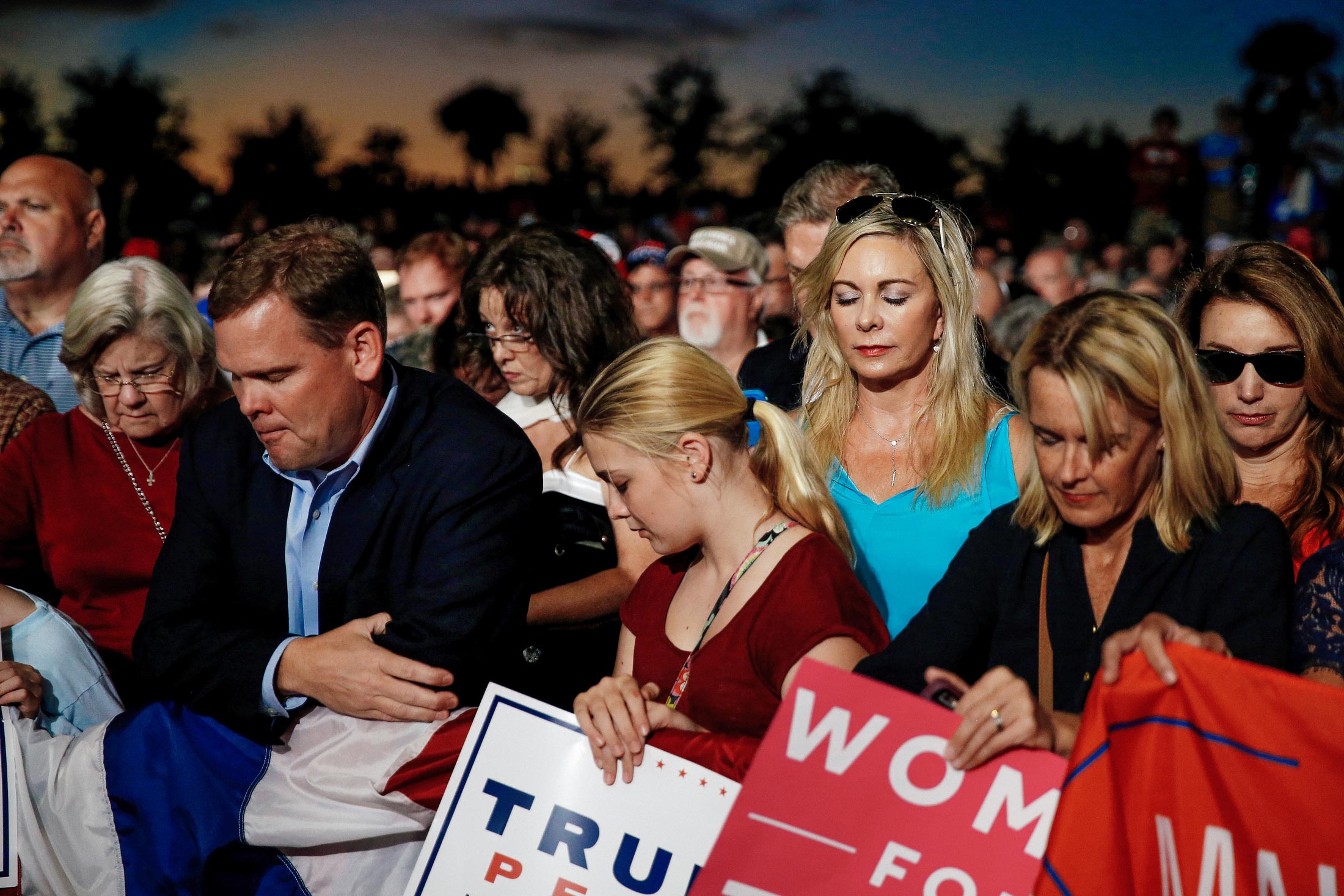 Supporters bow their heads in prayer before a Trump rally.