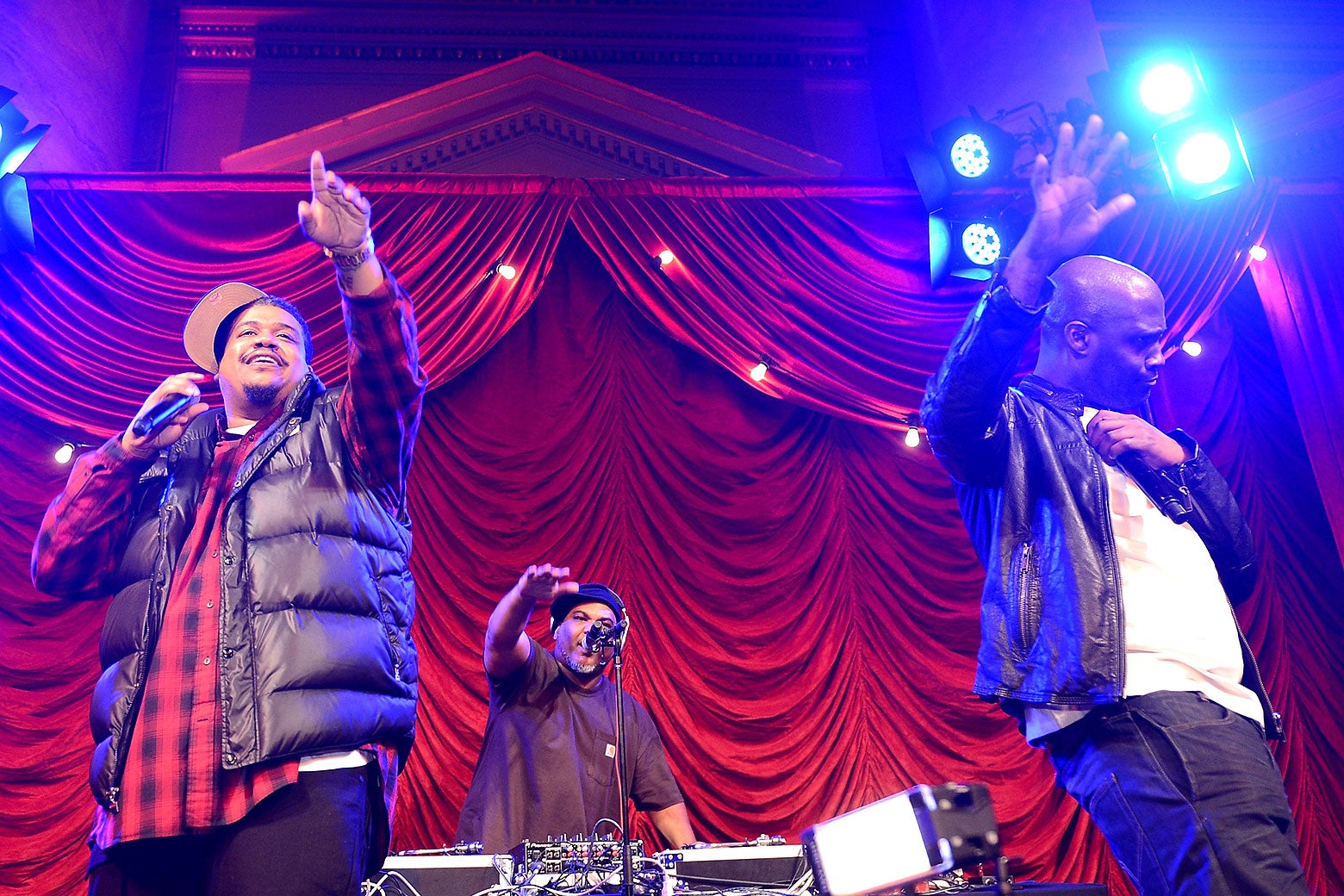 De La Soul performs a concert live on stage with their hands in the air.