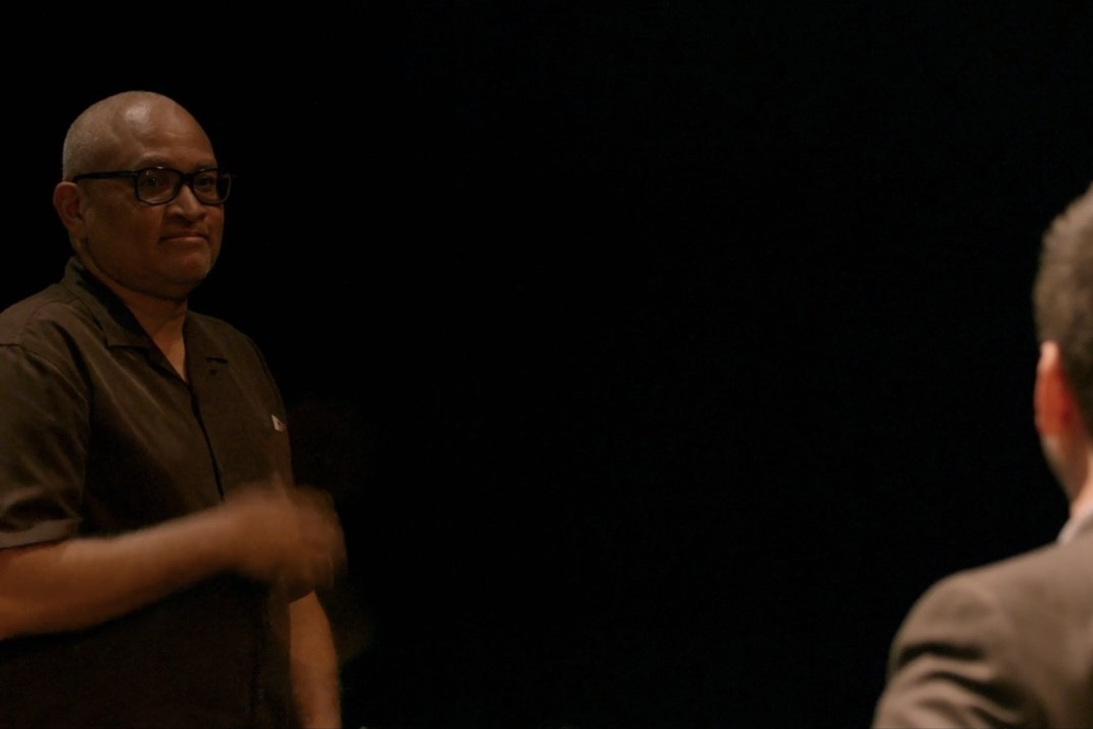 Larry Wilmore, standing against a black background in a theater.