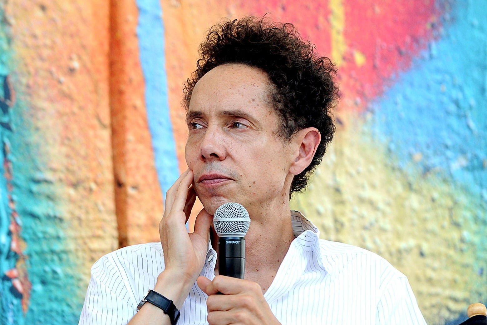 Malcolm Gladwell pondering a question while holding a microphone.