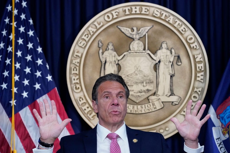 Andrew Cuomo gesticulates while speaking in front of the New York state seal.