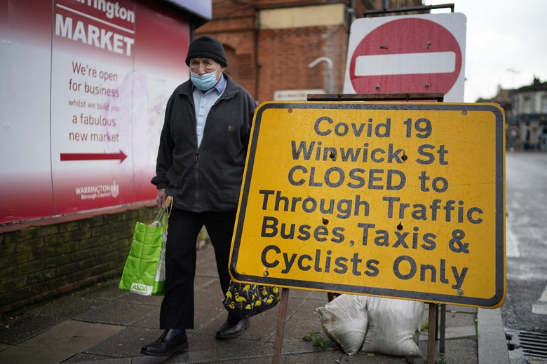 People wear face masks in the town centre of Warrington, England.