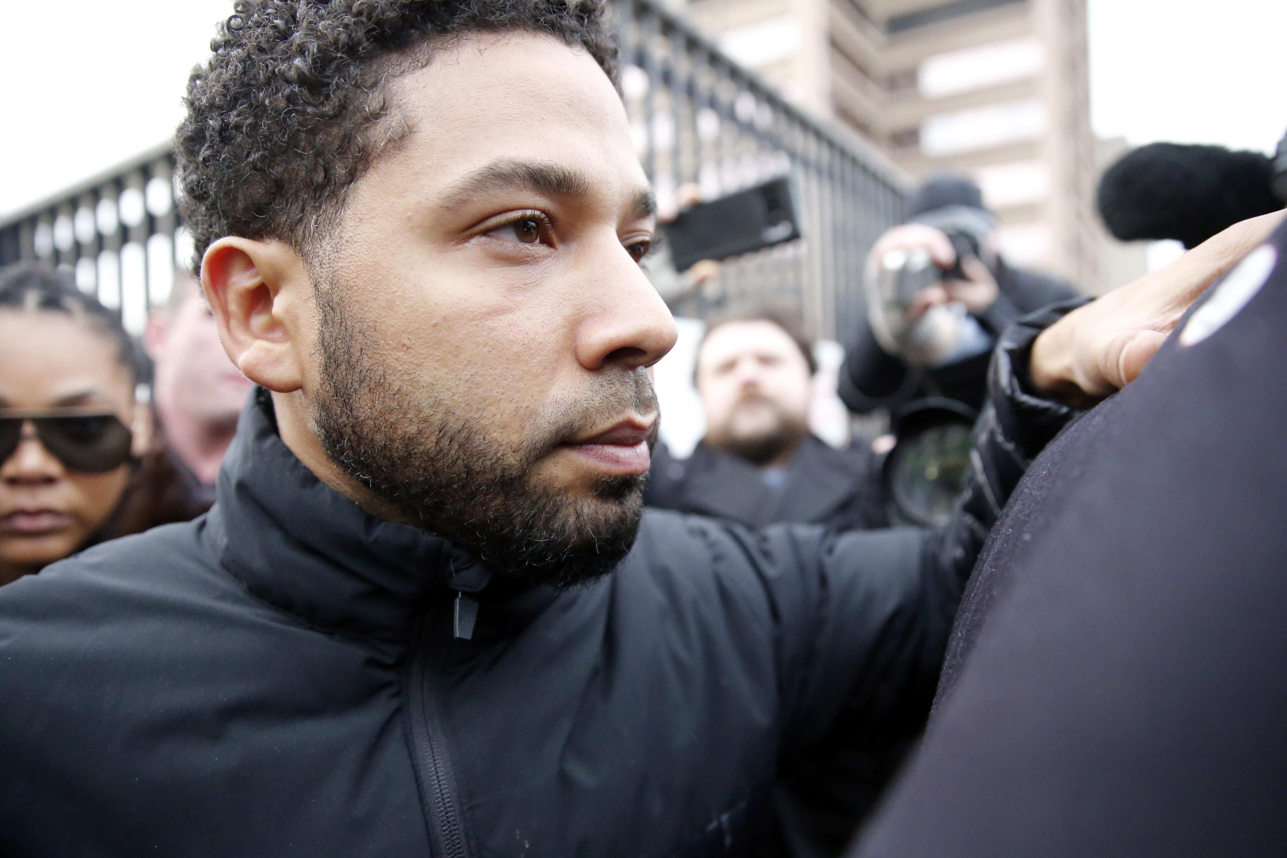 Jussie Smollett can be seen surrounded by a throng of people, some of whom have cameras.
