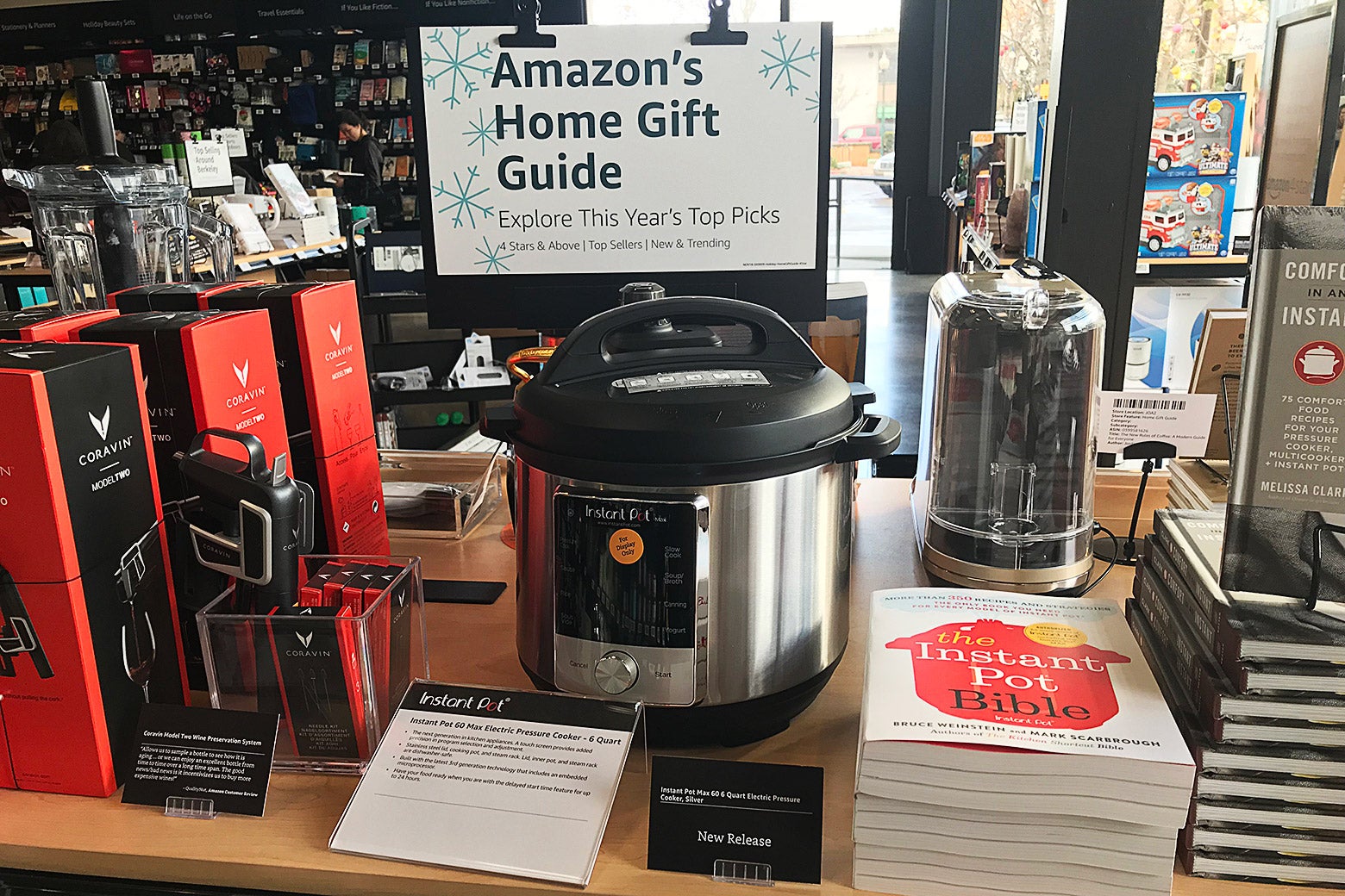A sign says "Amazon's Home Gift Guide" over an Instant Pot, other kitchen gadgets, and books.