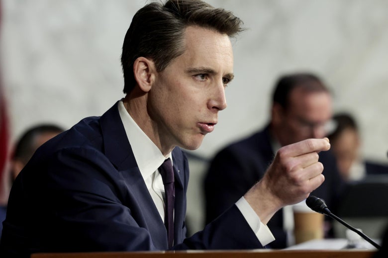 Josh Hawley gestures as he speaks into a microphone in a committee hearing room.