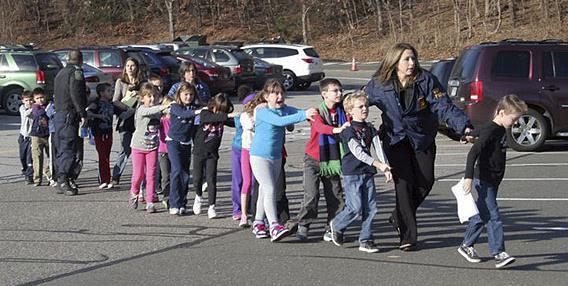 In this photo provided by the Newtown Bee, Connecticut State Police lead children from the Sandy Hook Elementary School in Newtown, Conn., following a reported shooting there Friday, Dec. 14, 2012. 