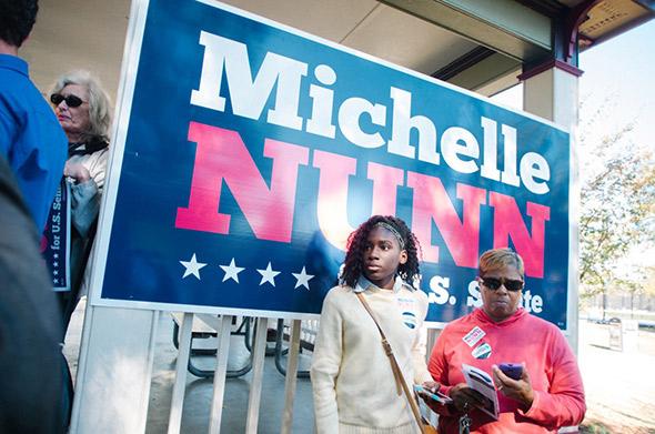 A young woman stands next to a ‘Michelle Nunn’ sign during a rally in Macon, Georgia.