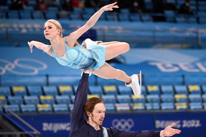 Morozov lifts Tarasova with one arm who sticks out her arms and one back leg like she's flying