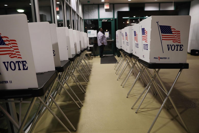 Two lines of voting booths with an American flag and the word VOTE on the side.