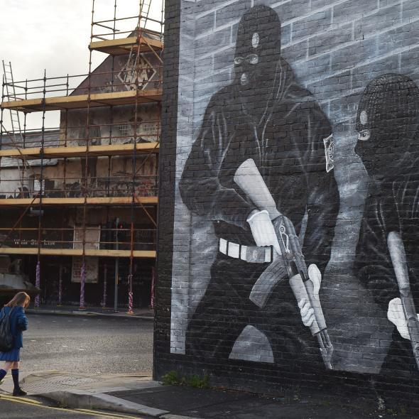 A schoolgirl walks past a loyalist paramilitary mural