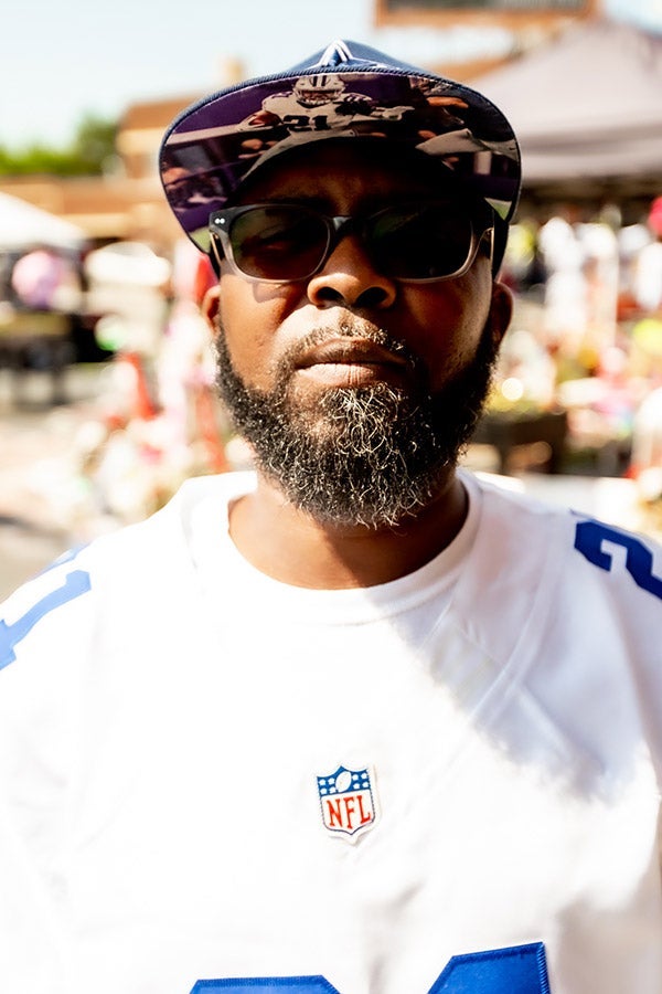 A man in sunglasses and a baseball cap wears an NFL jersey.