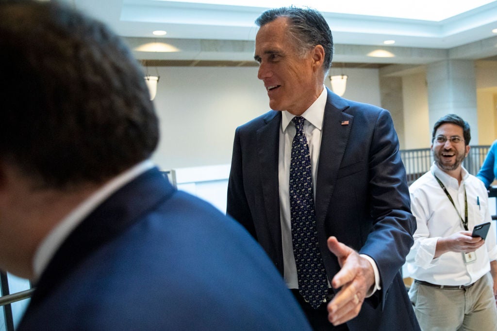 Romney smiles while walking through a busy hallway.