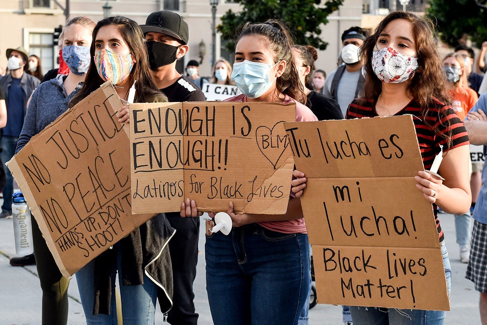 Young Latinos hold up signs in support of Black Lives Matter at a protest