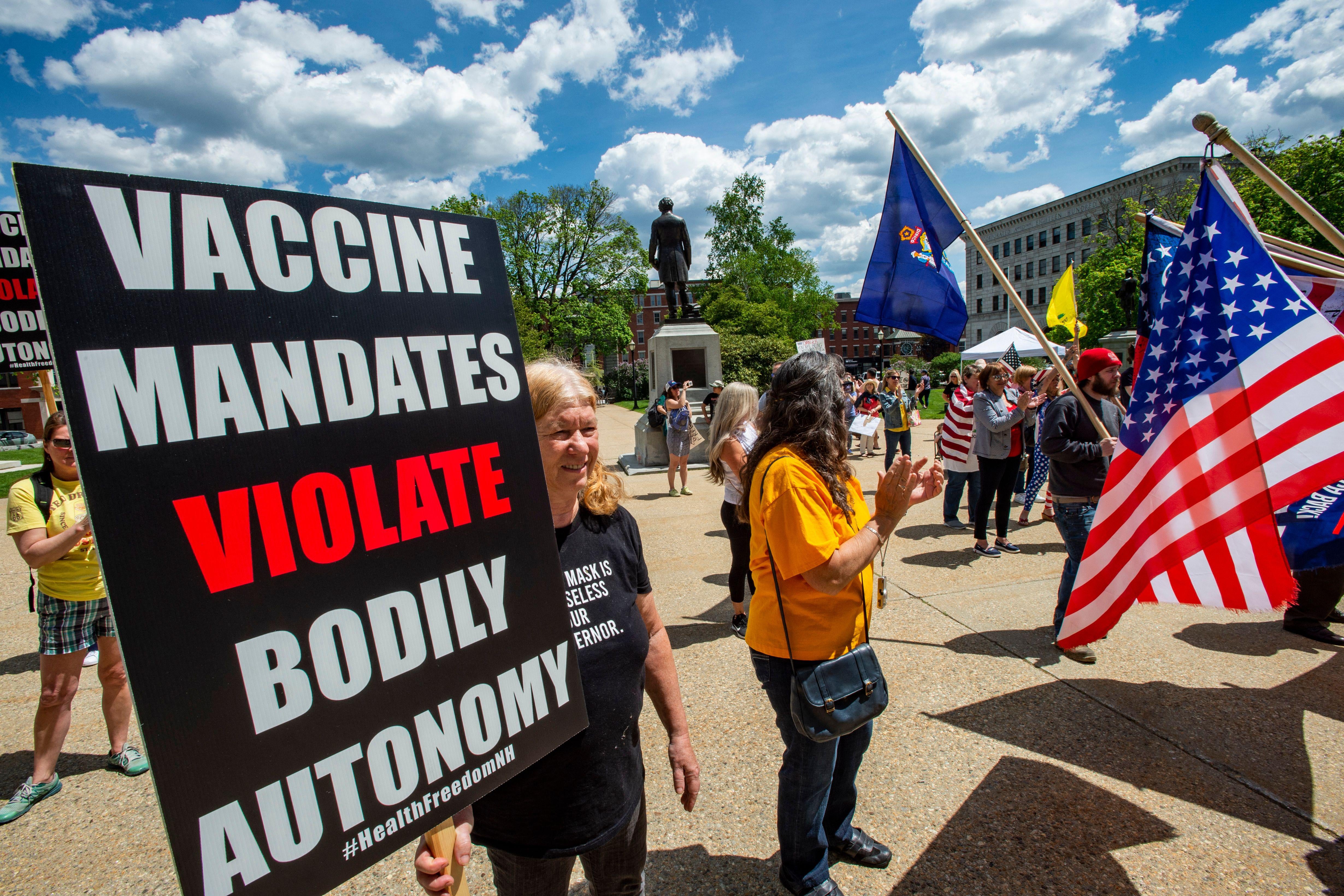 A woman holds a sign that says, "VACCINE MANDATES VIOLATE BODILY AUTONOMY."