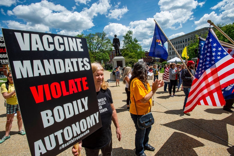 A woman holds a sign that says, "VACCINE MANDATES VIOLATE BODILY AUTONOMY."