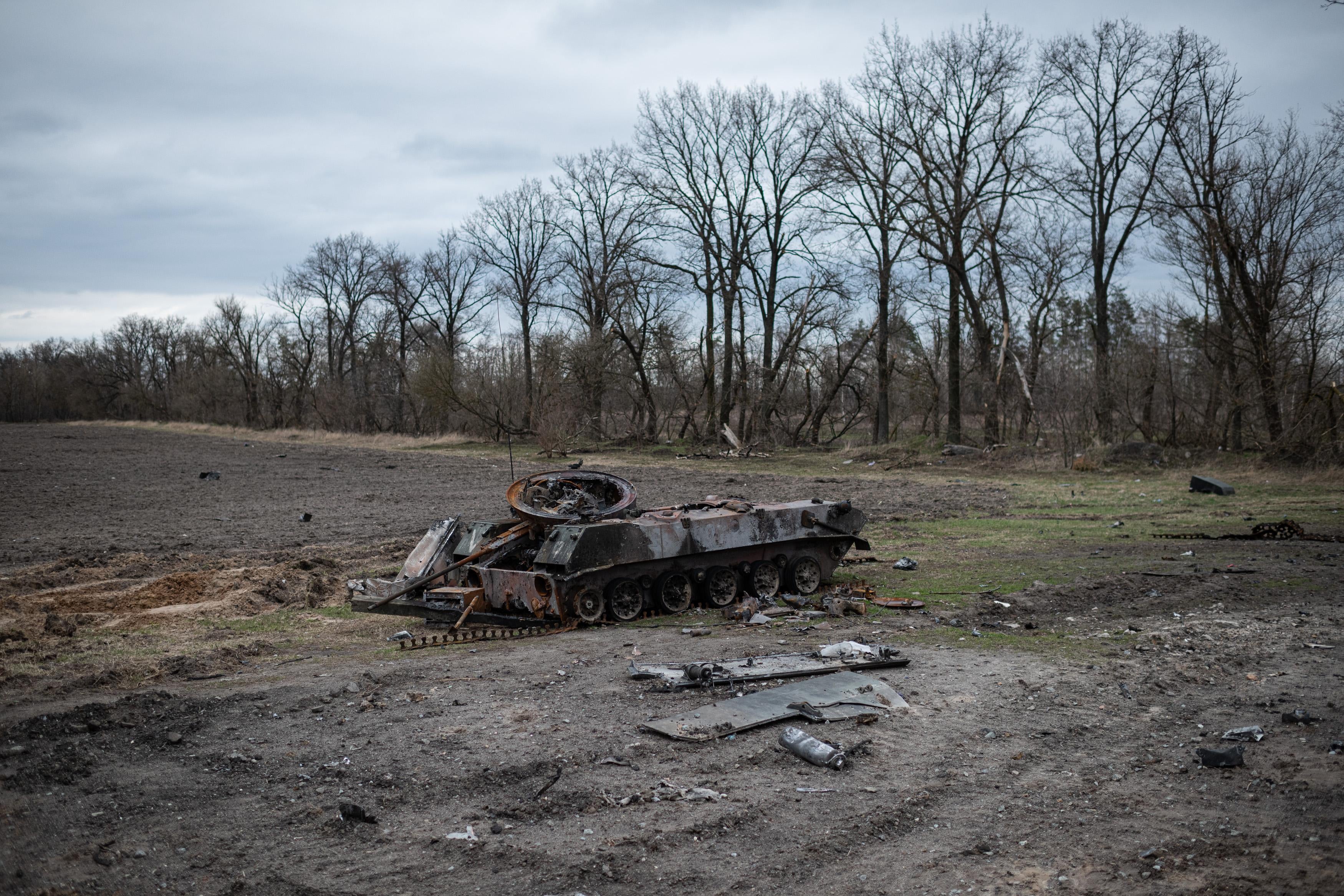 A burnt tank in the middle of an empty field.