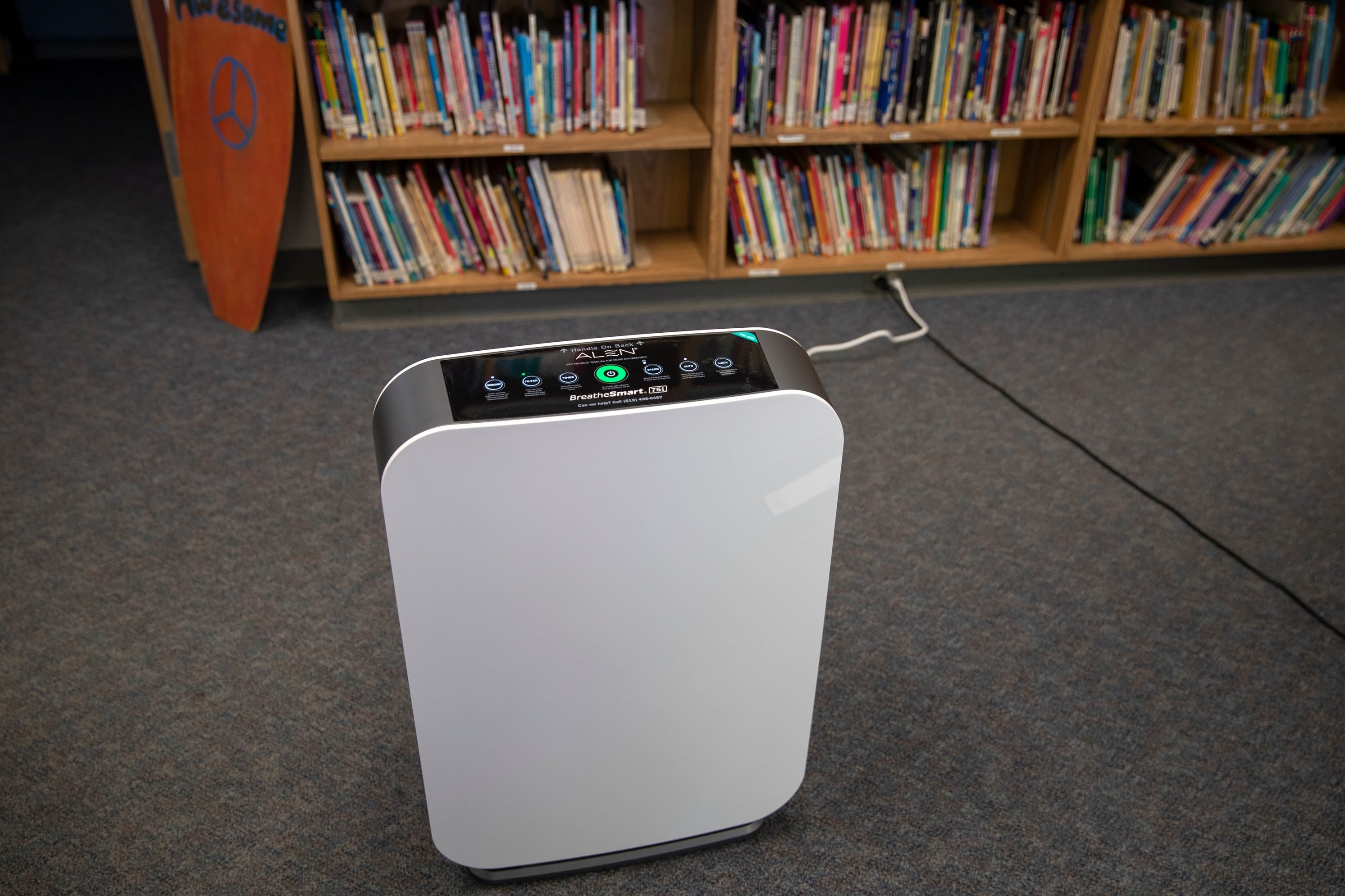 An air purifier is seen in front of a bookshelf.