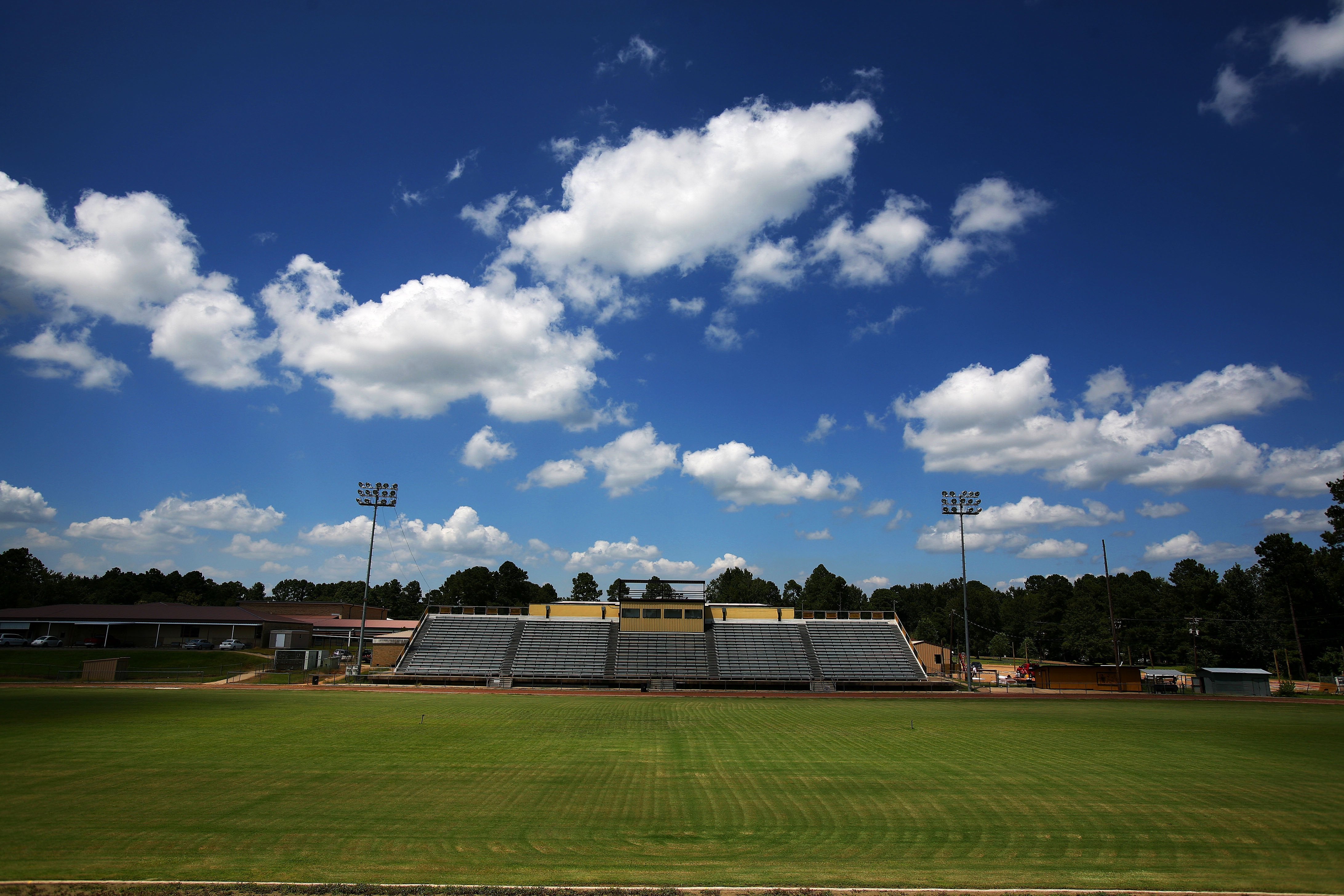 A freshly mowed football field, featuring empty bleachers.