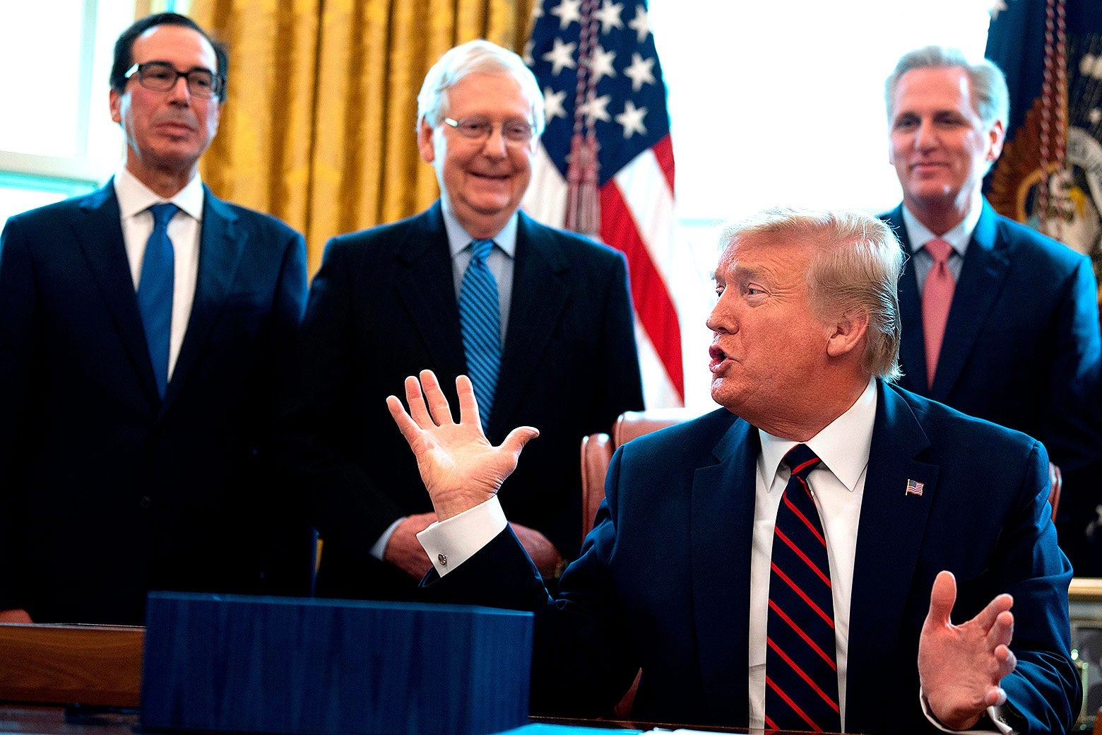 Donald Trump raises he hands while speaking to Steve Mnuchin, Mitch McConnell, and Kevin McCarthy.