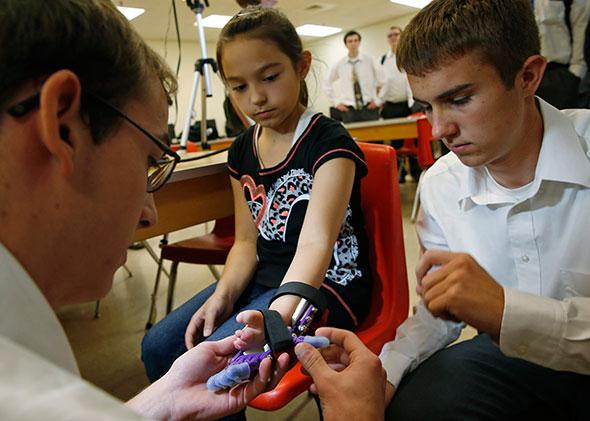 Bud May (L), a teacher at Boylan Catholic High School shows a prosthetic hand made for Kylie Wicker (2nd R), as her parents Jeromy (2nd L) and Sharon look on in Rockford, Illinois, May 2, 2014. The Engineering Graphics class at the school took on the project of making a prosthetic hand for Wicker, who was born without fingers on her left hand, using a 3-D printer and instructions that were posted online.