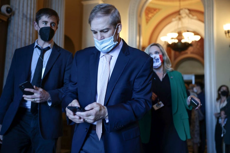 Jordan, wearing a mask over his mouth but not his nose, types on his phone as he walks through the Capitol