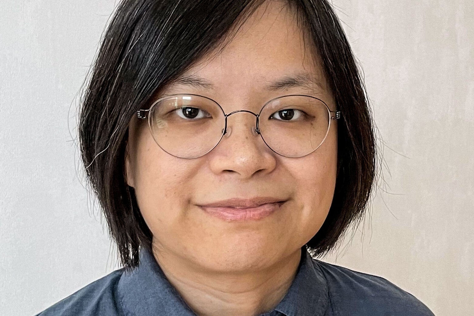 A bespectacled Asian woman stares confidently into the camera.