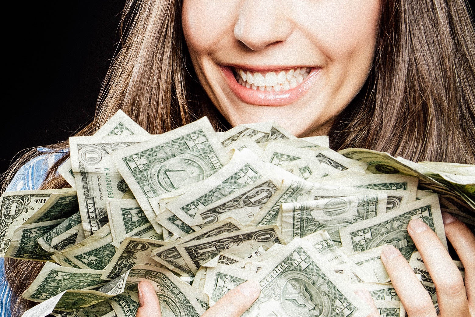 A woman cradles a large pile of cash.