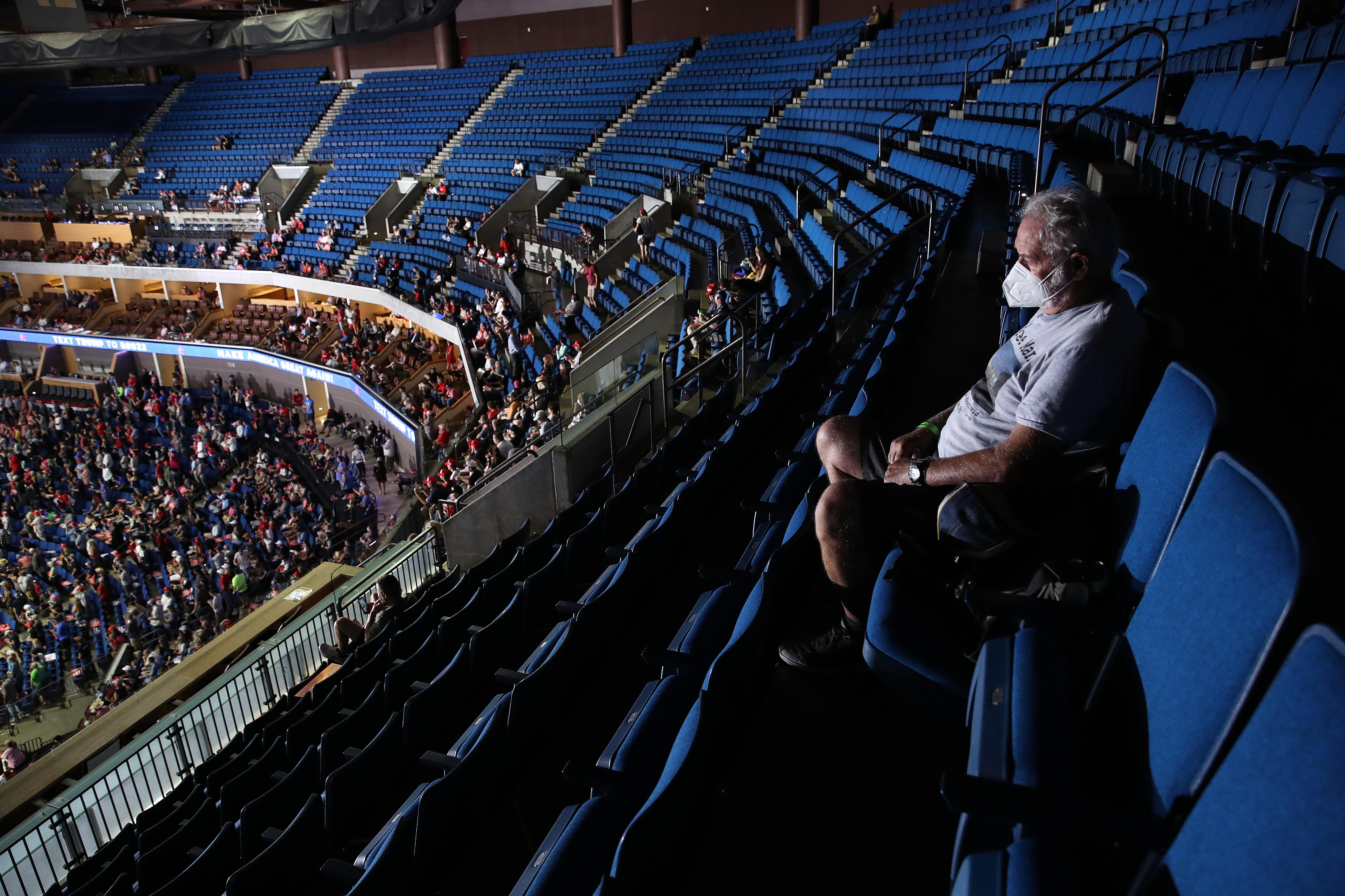 A Trump supporter sits in the upper tier of the arena, which is almost completely empty.