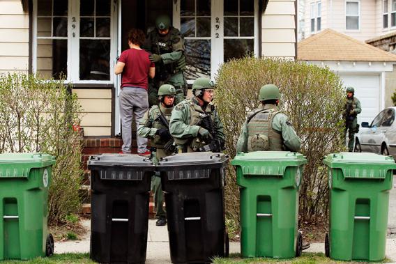 Residents watch as police officers search house to house for the second suspect in the Boston Marathon bombings in a neighborhood of Watertown, Massachusetts April 19, 2013.  