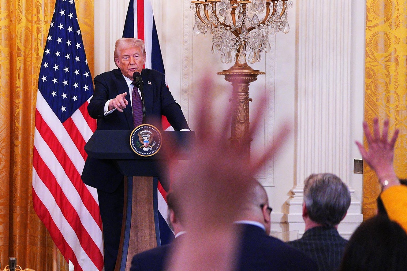 Donald Trump points at a reporter from behind a lectern at a White House Press Briefing.