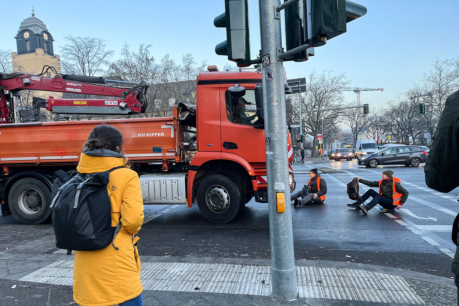 Two Letzte Generation activists try to stop a truck that has forced its way through a partially blocked intersection.