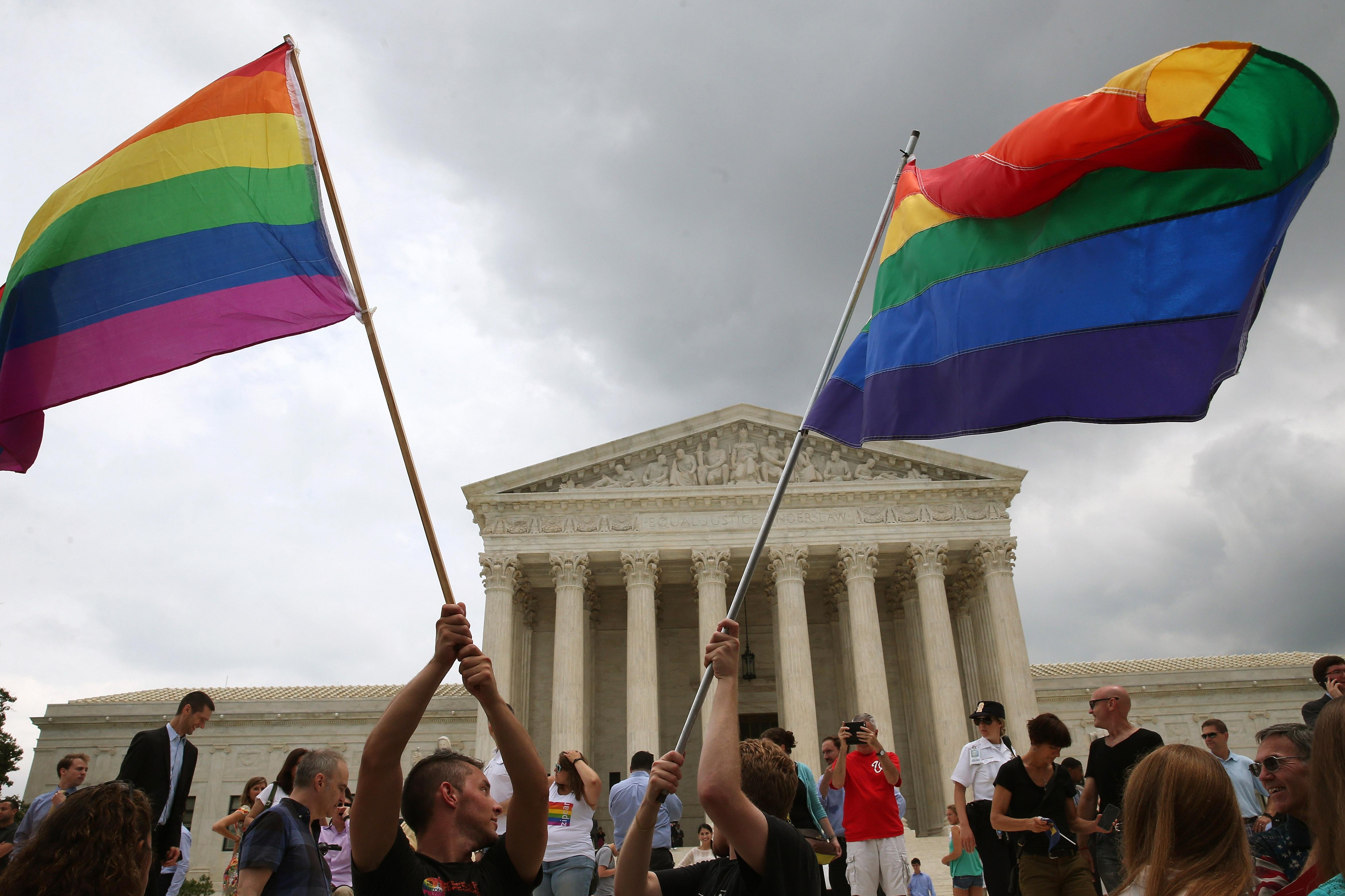 People wave rainbow flags outside the Supreme Court.