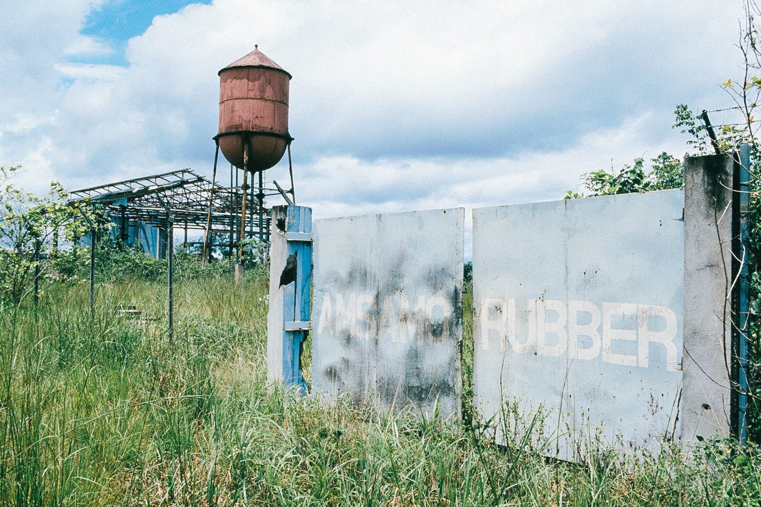 A burned, faded sign bearing the name of a rubber brand is seen in front of a water tower.
