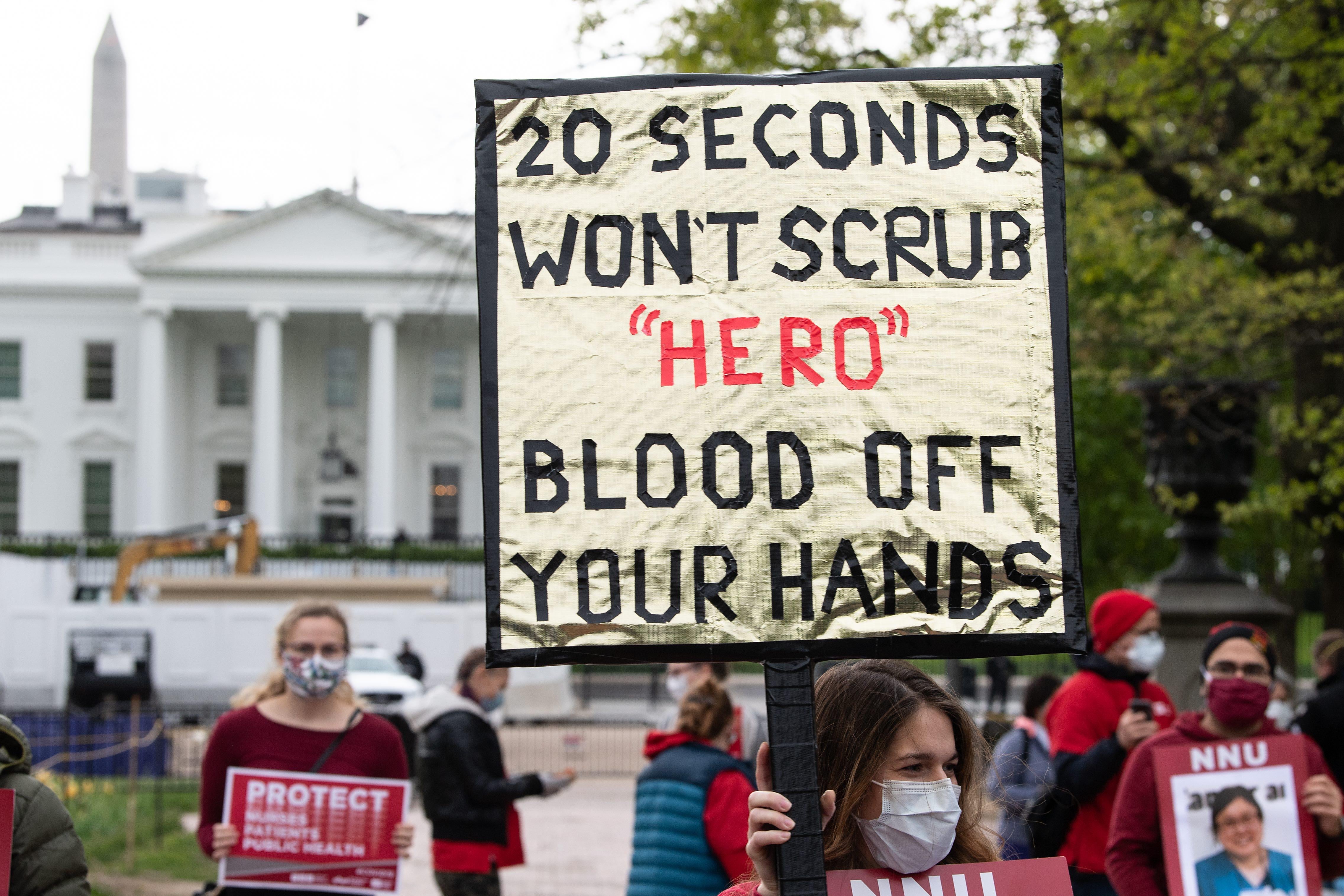 A protester holds a sign that reads "20 seconds won't scrub 'hero' blood off your hands"