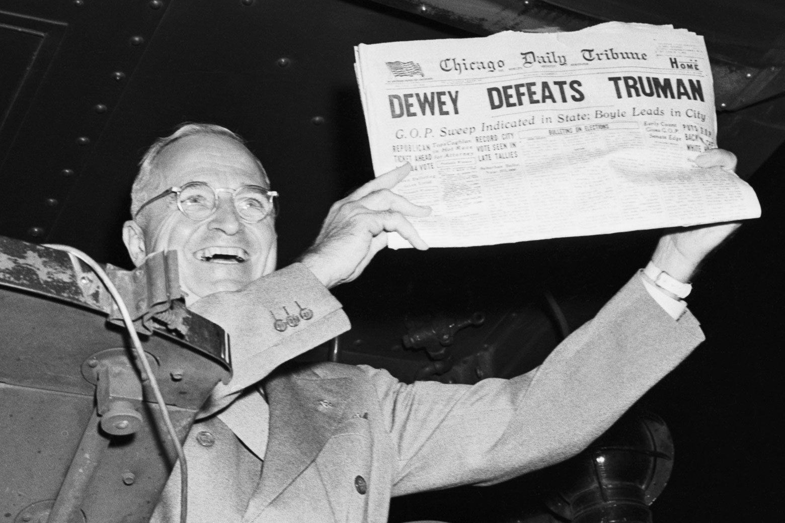 Historic black-and-white photo of Truman holding a newspaper with the headline "Dewey Defeats Truman" up  for the camera.