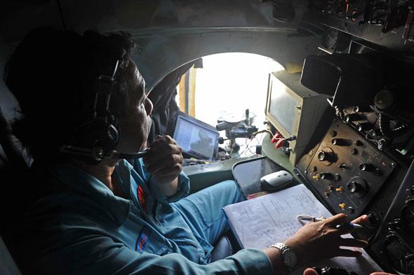 A crew member looks out the window of a search aircraft during search operations for missing Malaysia Airlines flight 370 over the southern seas off Vietnam on March 9, 2014.