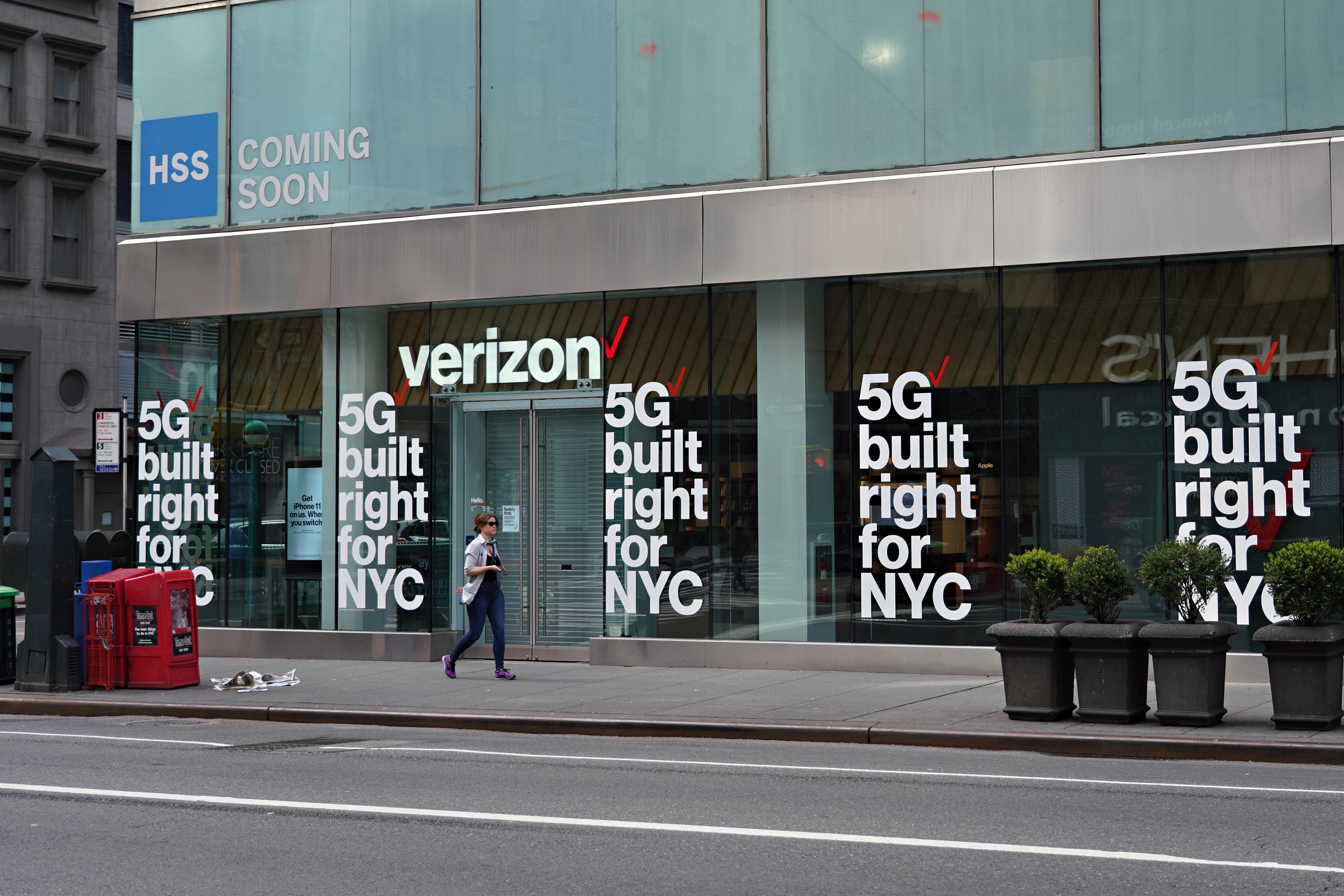 A person walks by a Verizon storefront with signs that say "5G built right for NYC."