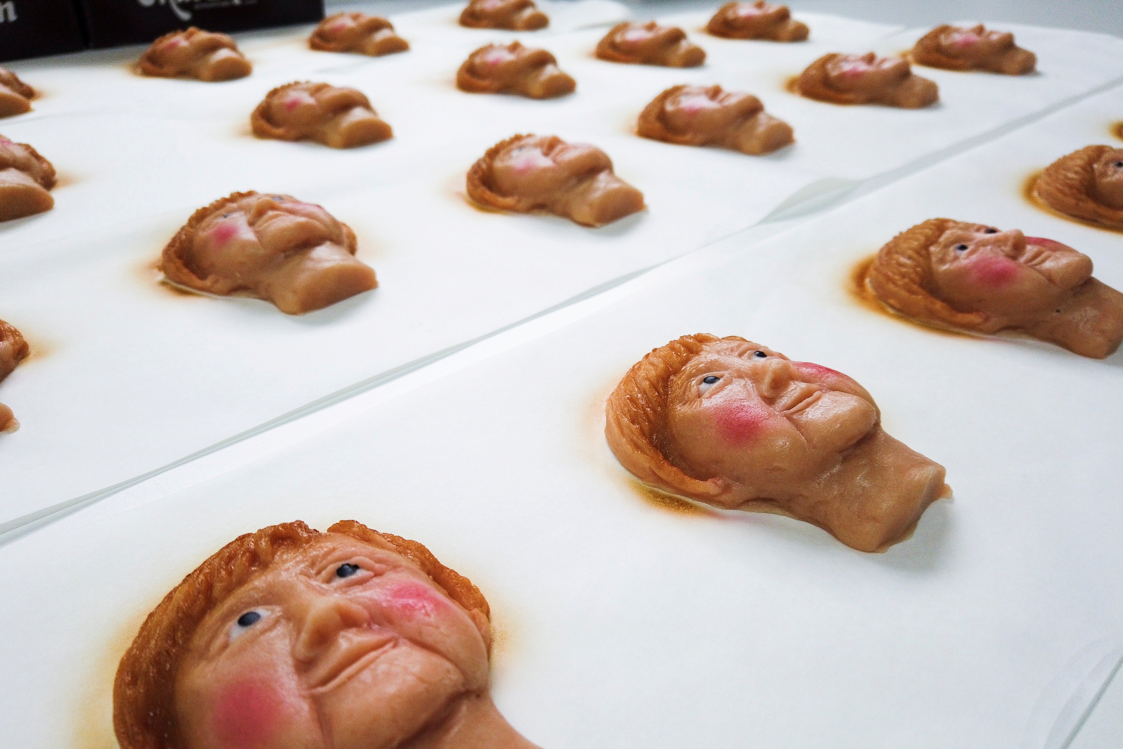 Cookies portraying Angela Merkel's face are seen on a sheet.
