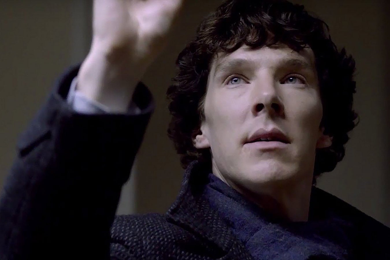 Benedict Cumberbatch as Sherlock wears a scarf and blue-ish ensemble and looks upward.