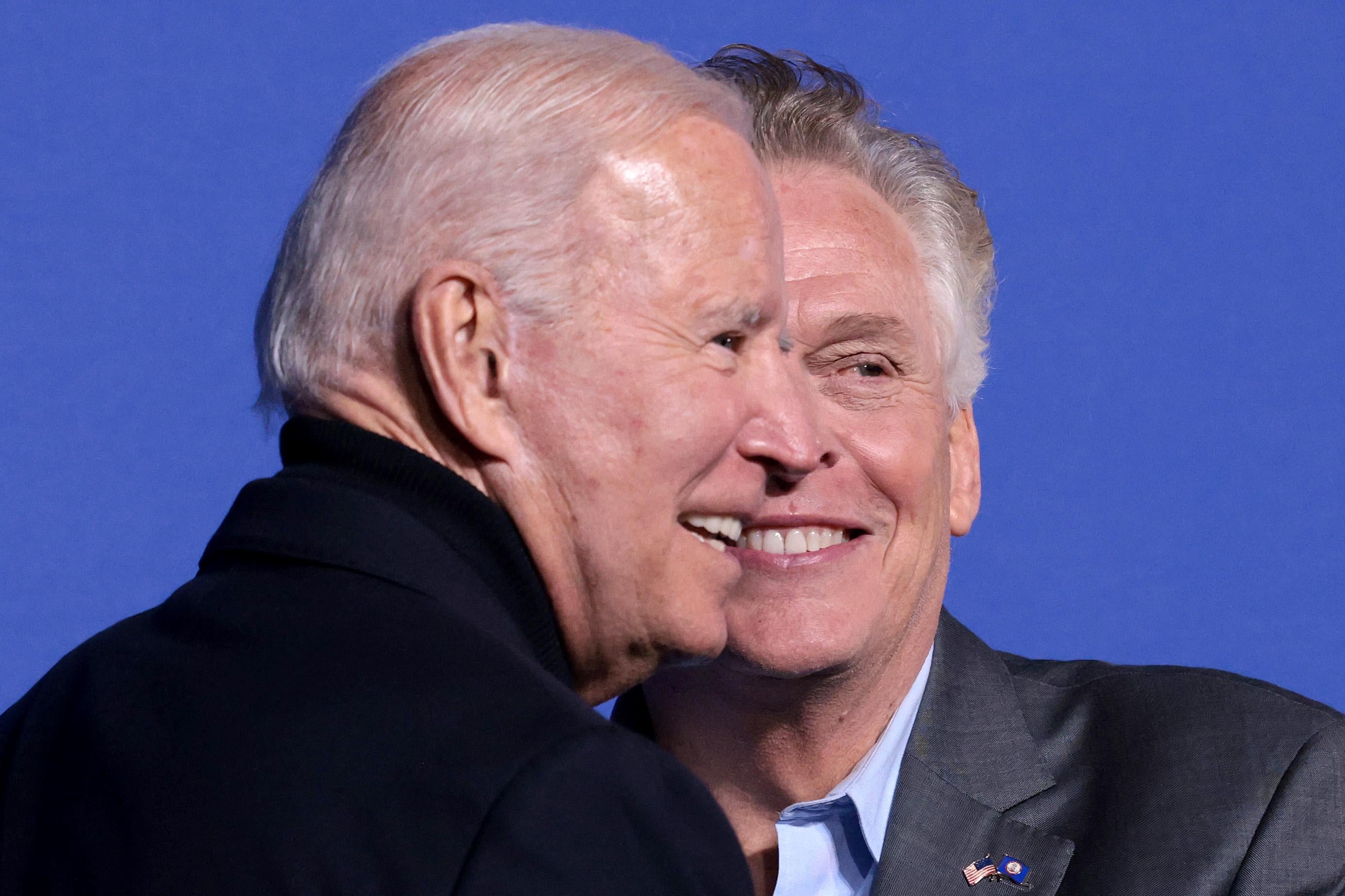 Biden and McAuliffe stand smiling with their faces cheek to cheek