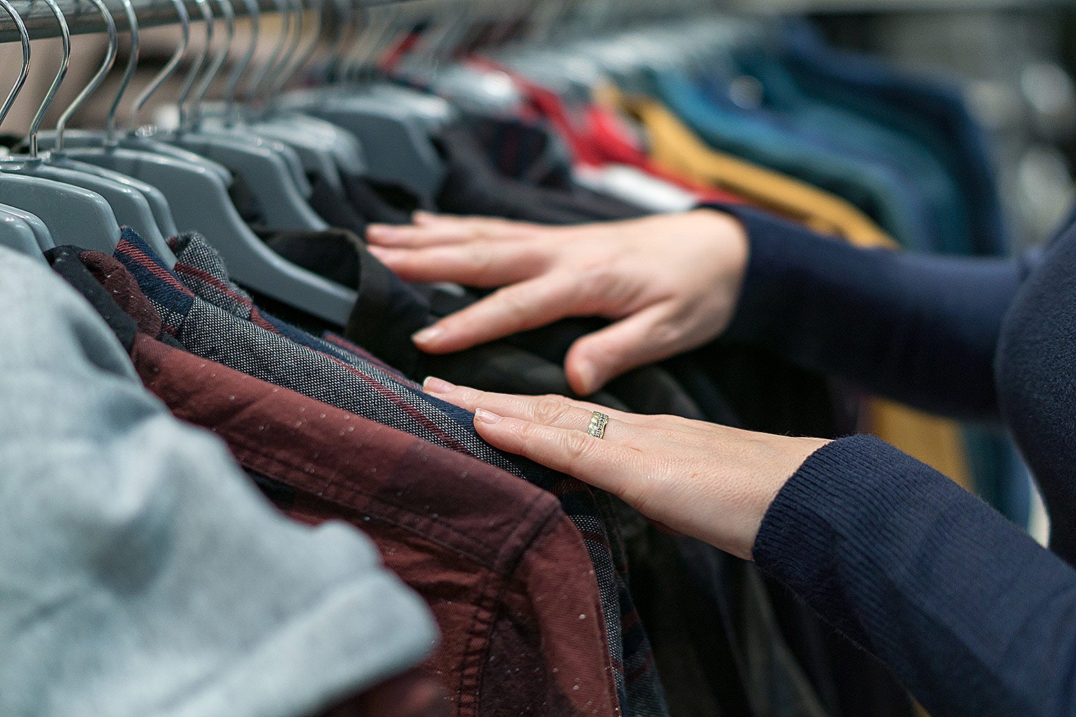 Stock image of a person searching through a rack of clothing.