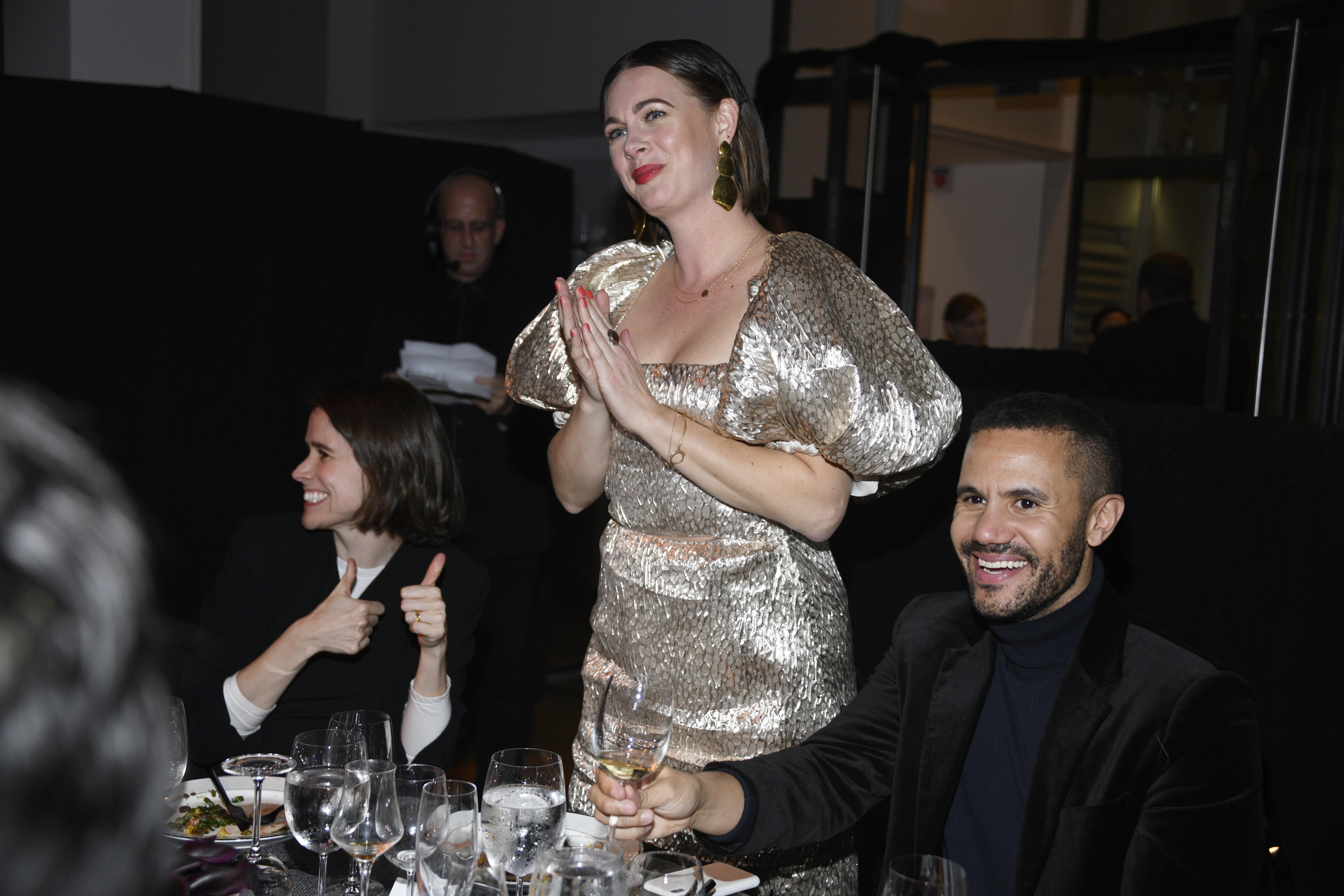 Alison Roman, in a platinum dress with puffy sleeves, stands at a dinner table smiling with her hands clasped together as she attends "The Bloomberg 50" Celebration at The Morgan Library on Dec. 9, 2019 in New York City.