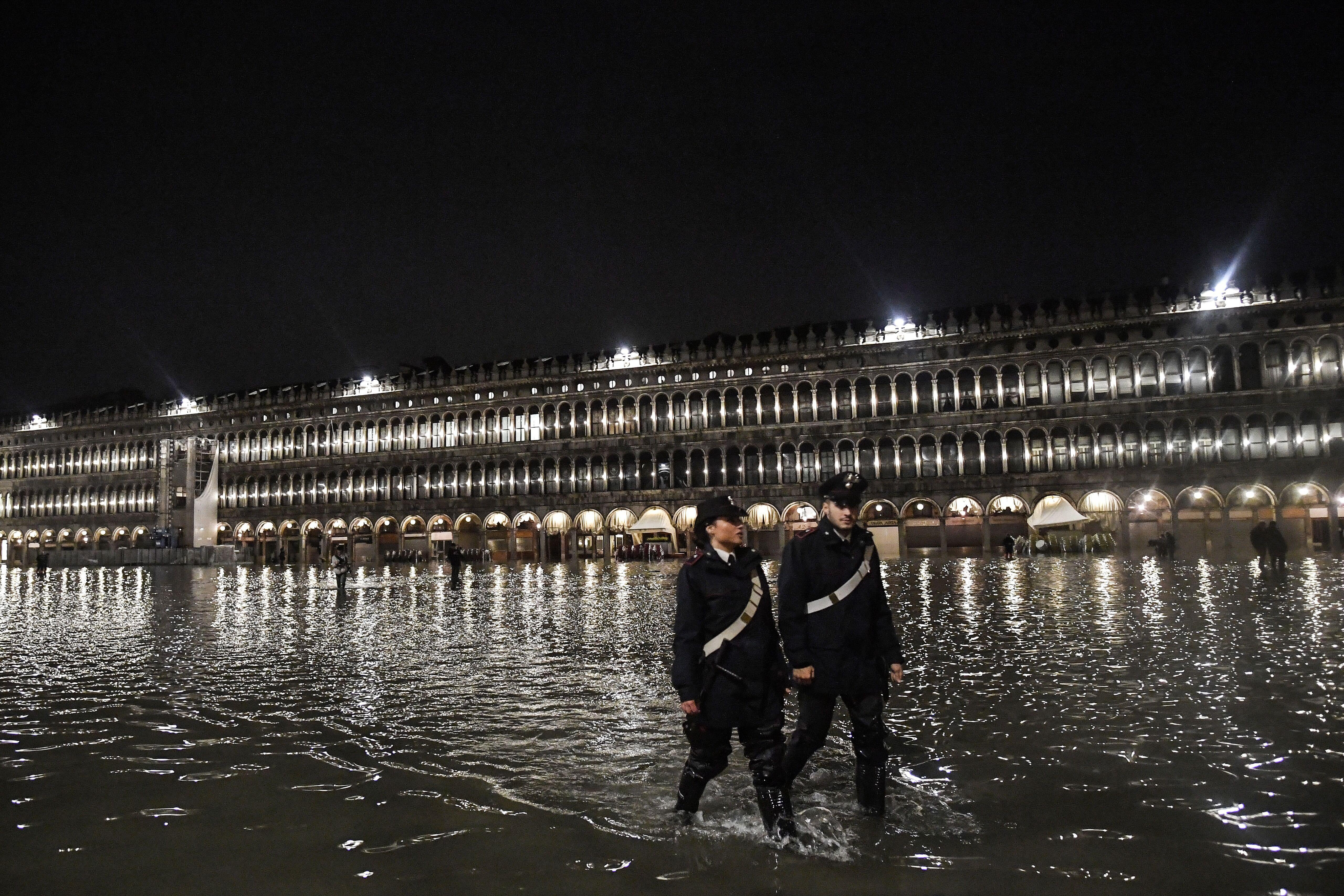 Police patrol across the flooded St. Mark’s Square.