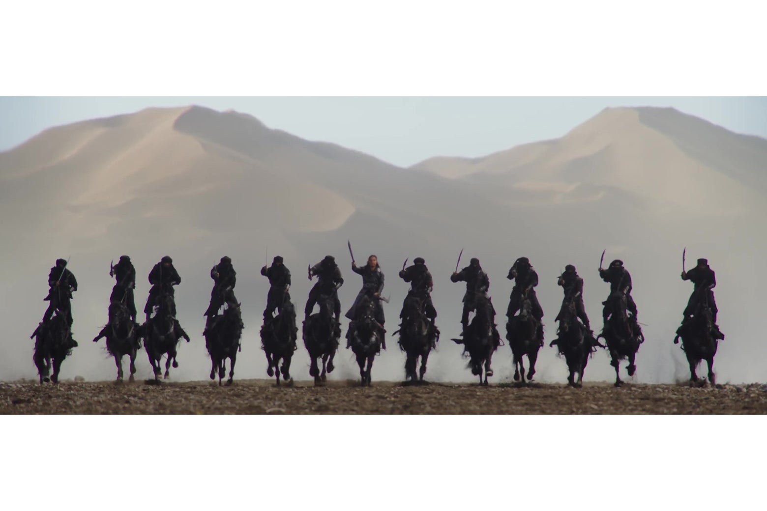 13 soldiers on horseback, riding in a row straight at the camera, in a still from Mulan.