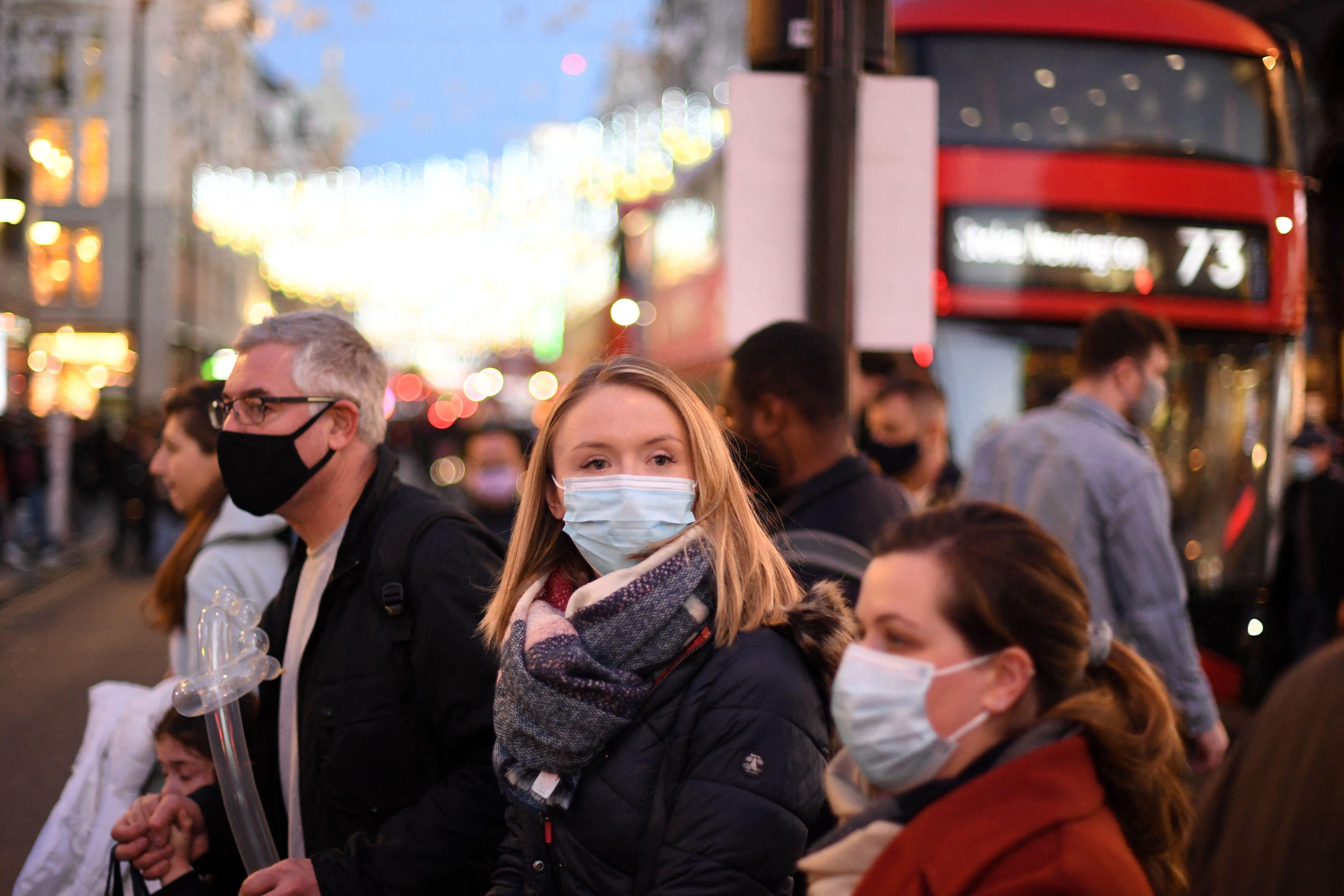 Shoppers, some wearing face coverings, cross Oxford Street in central London on December 4, 2021.