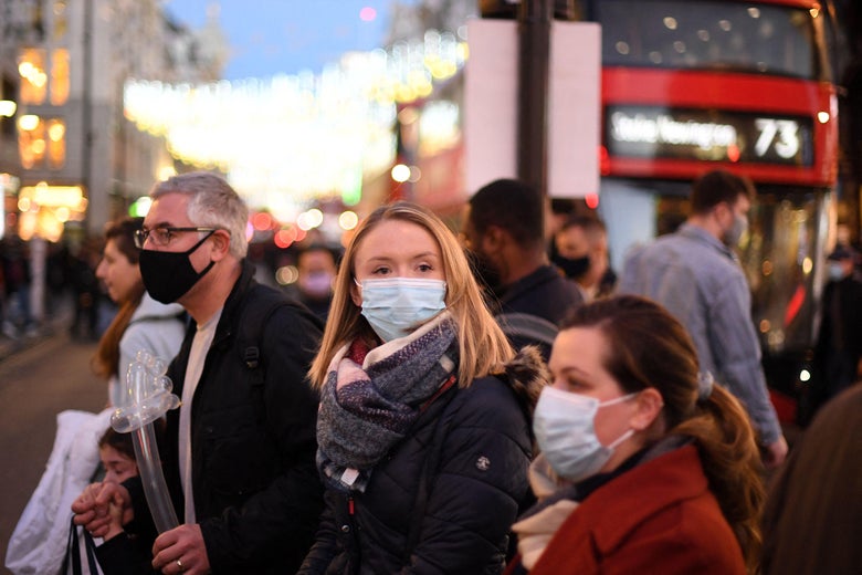 Shoppers, some wearing face coverings, cross Oxford Street in central London on December 4, 2021.