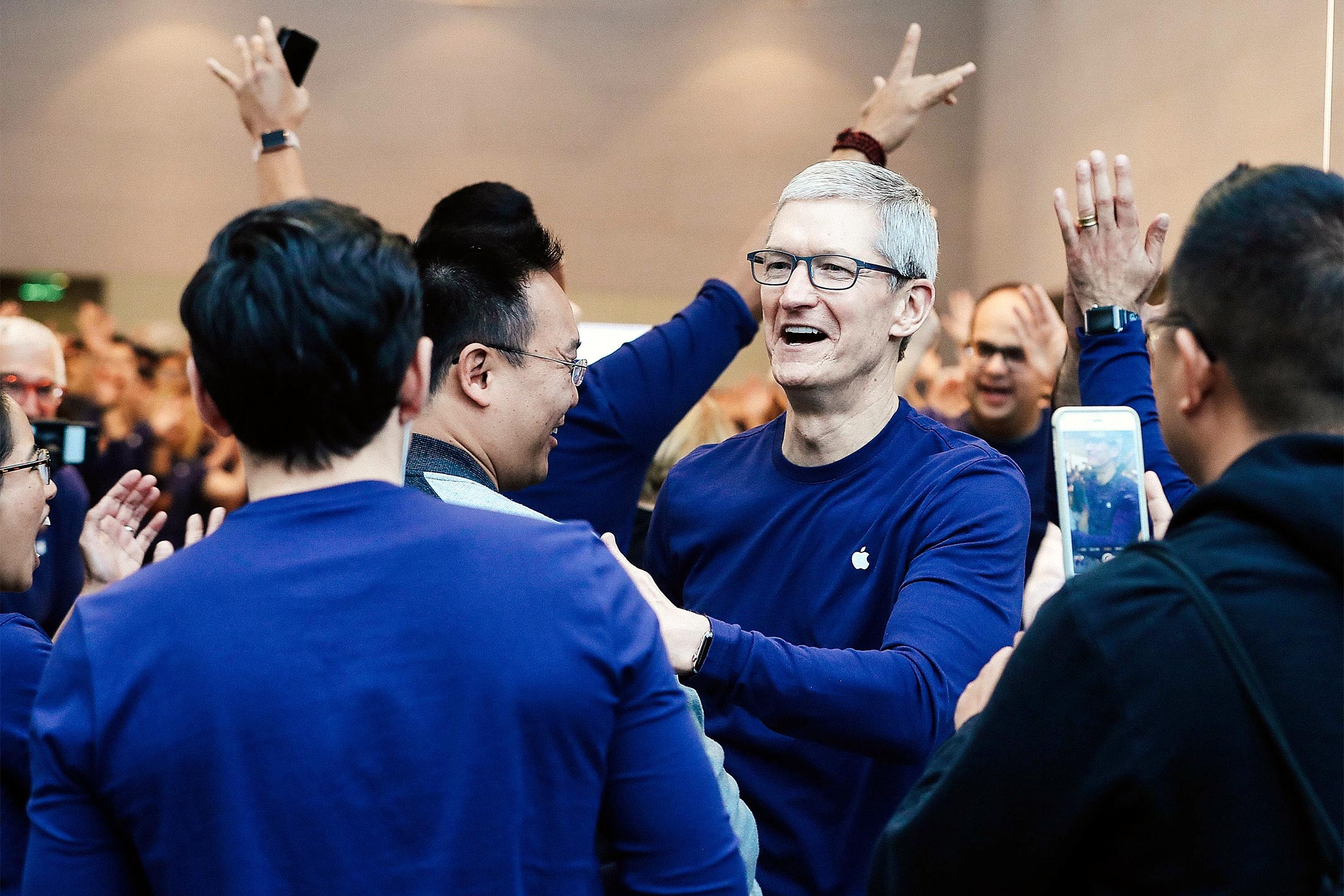 Tim Cook wears a long-sleeved Apple T-shirt as he greets customers for the iPhone X release at an Apple Store.