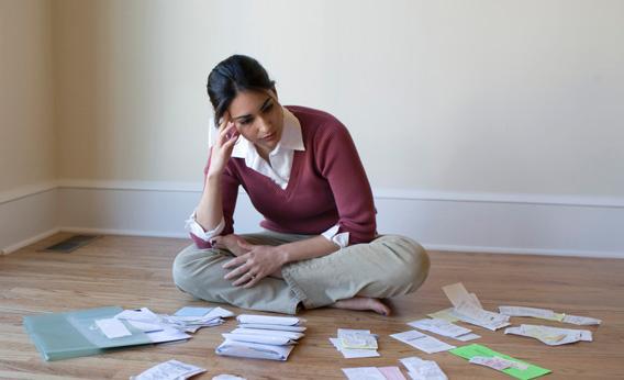Woman sits in front of bills and receipts.