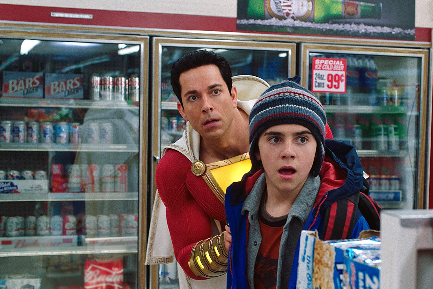 Zachary Levi, wearing a red, caped superhero suit, and Jack Dylan Grazer in a convenience store.